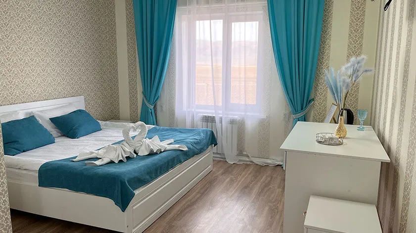 Номер с бирюзовыми шторами и большим окном